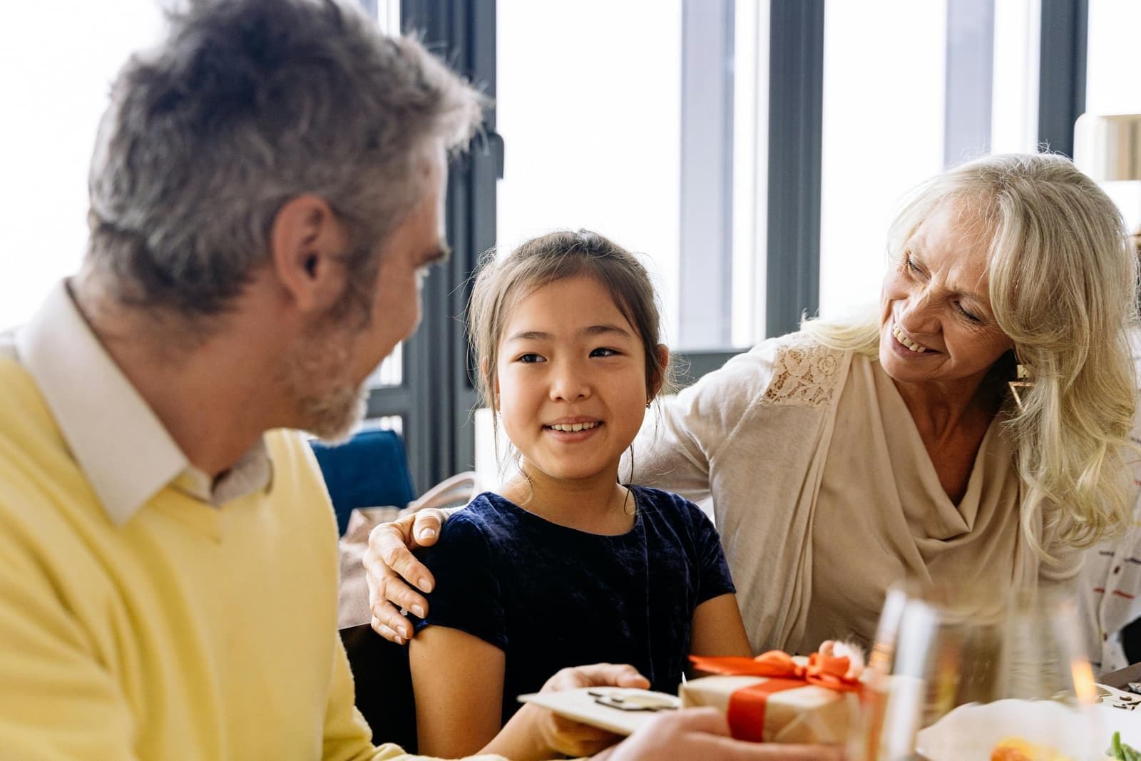 Grandparents smiling with a young child at a family gathering.
