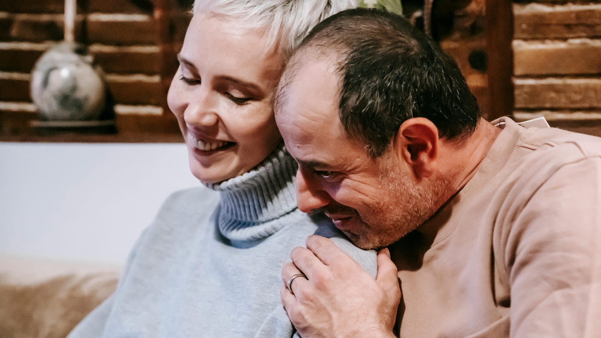 A man embraces a woman from behind while they share a joyful moment together.